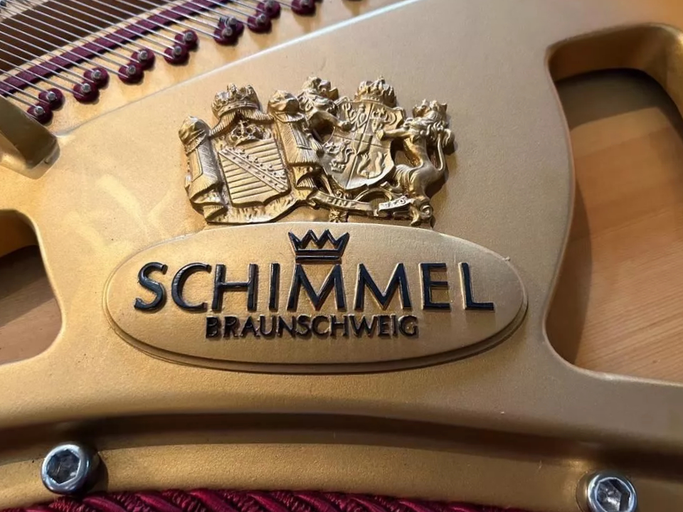 detail of Schimmel grand piano frame with manufacturer's crest